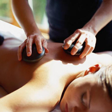 Vrouw krijgt een mixed lichaamsmassage, met verwarmde hotstone massagestenen.